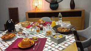A dining table set with various food items, a mirror, and a vase on a patterned wall.
