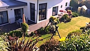 A modern two-story house with a patio, large windows, and a well-maintained garden.