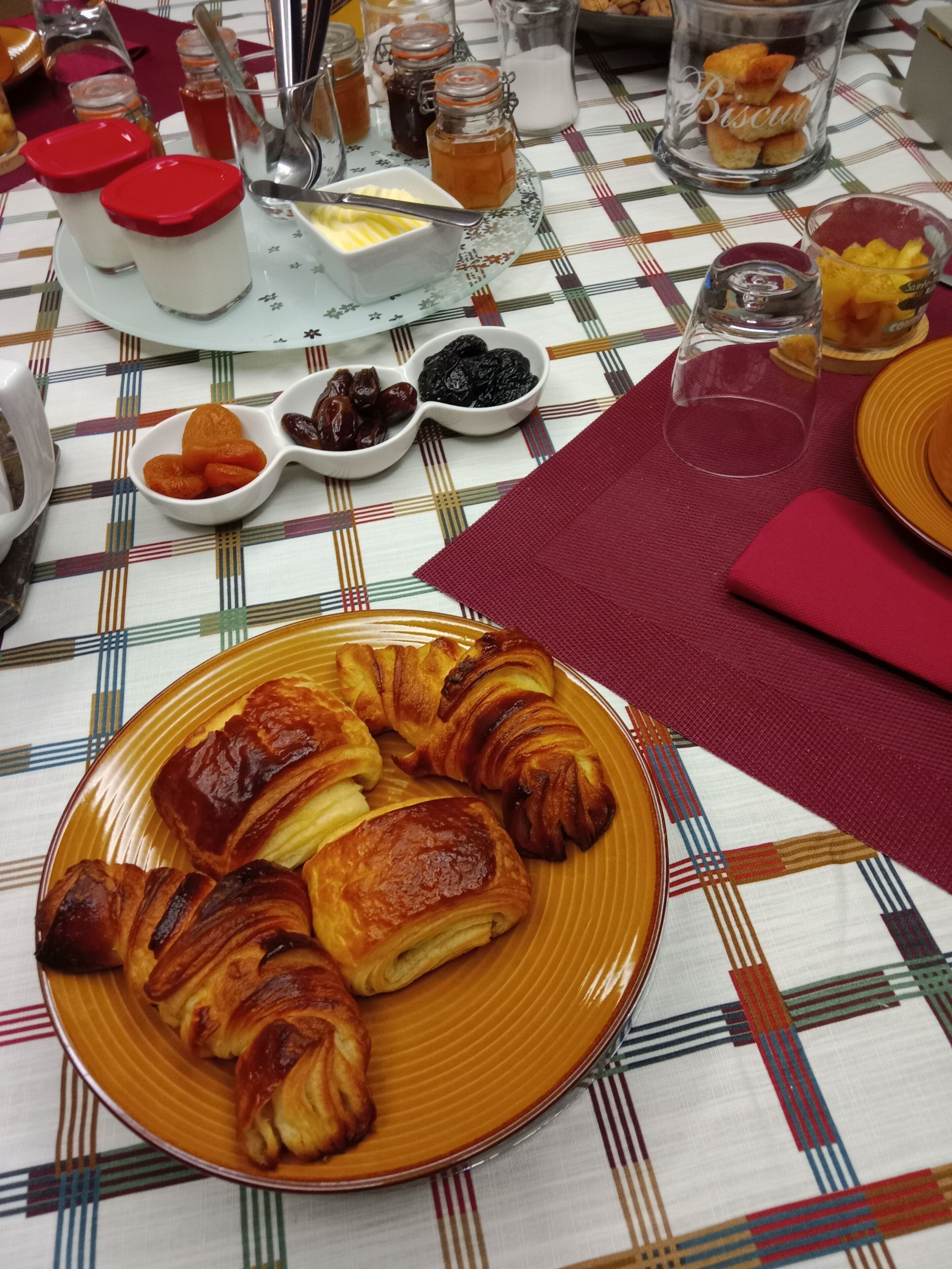 Un desayuno con pastelería, salsas y un mantel a cuadros.