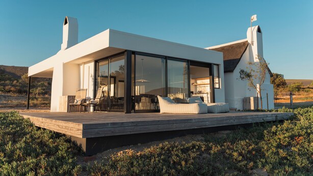 Una casa moderna con terraza, ventanas amplias y una chimenea.