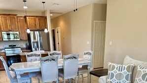 A modern living room with a dark wooden coffee table, light-colored sofa, patterned rug, and a dining area with a light blue table and matching chairs. - 3-bedroom house in pleasant Fischer with big secluded backyard (Fischer)