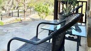 A covered patio area with outdoor furniture, a potted plant, and a view of trees and a fence. - 3-bedroom house in pleasant Fischer with big secluded backyard (Fischer)