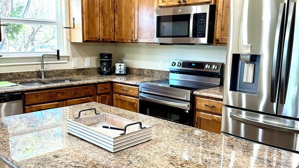 A kitchen with wooden cabinets, granite countertops, stainless steel appliances, and pendant lighting. - 3-bedroom house in pleasant Fischer with big secluded backyard (Fischer)
