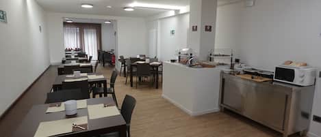 A hotel room with a dining area, kitchenette, and a view of the street.
