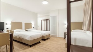 Habitación de hotel con dos camas, un escritorio, una silla y un radiador.