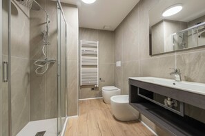Une salle de bain moderne avec une douche à parois de verre, des toilettes et un meuble-lavabo avec un miroir.