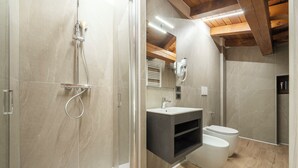 Un baño moderno con cabina de ducha de vidrio, techo de madera y un inodoro blanco.
