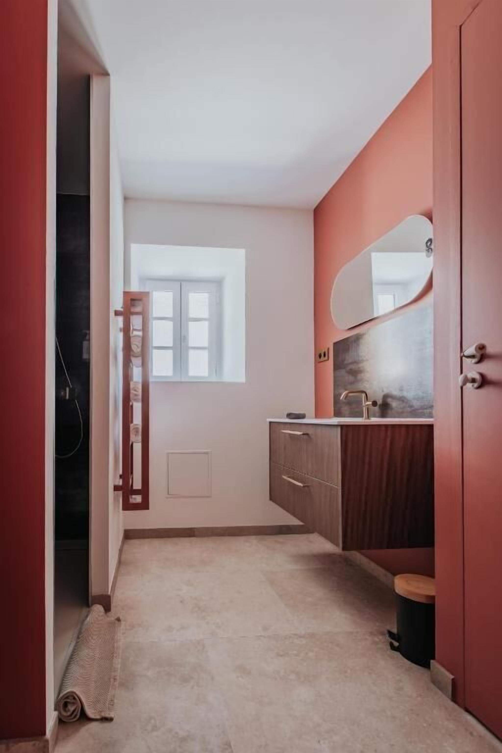 Een badkamer met een houten wastafelmeubel, een spiegel en een raam.