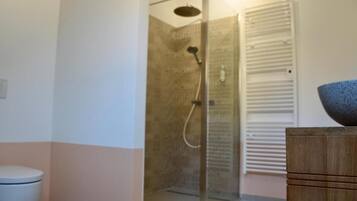 Un baño con inodoro, ducha con cerramiento de vidrio y armario de madera.