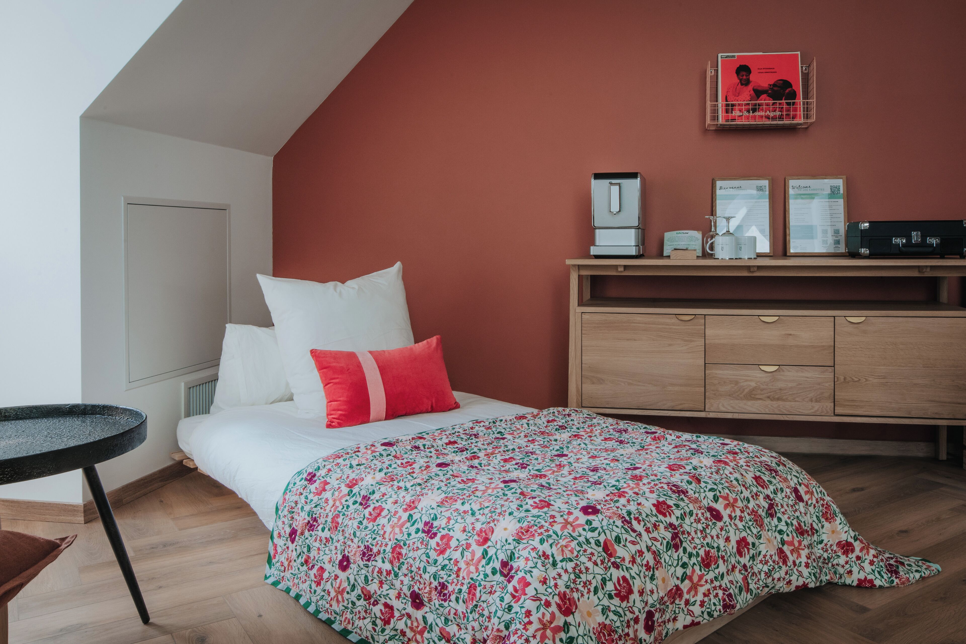 Une chambre à coucher avec un lit, une commode, une petite table et un radiateur.