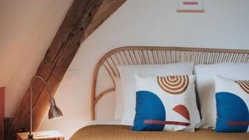 A bedroom with a wooden ceiling, a bed with a headboard, and a wall-mounted sign.