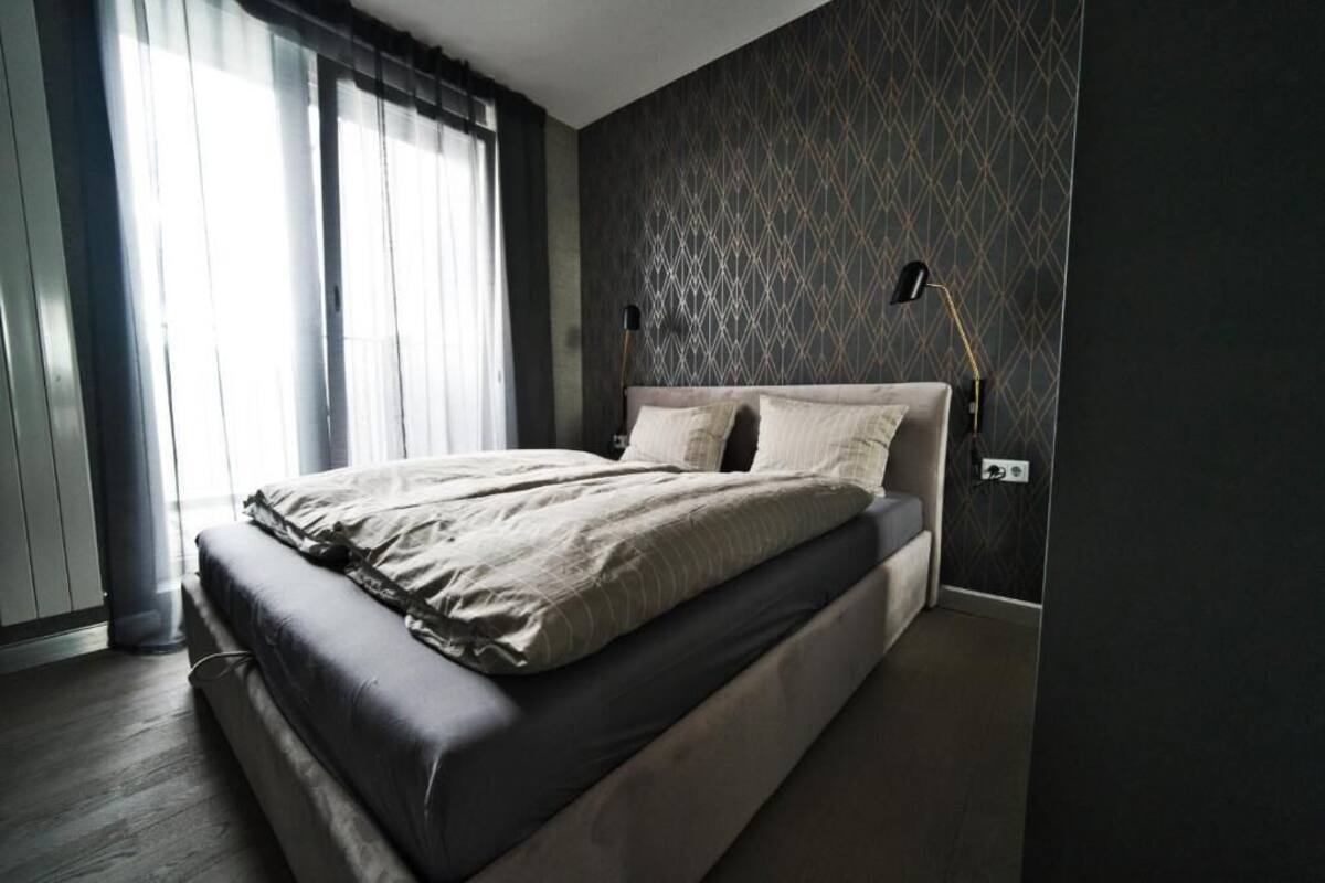 Une chambre moderne avec un grand lit, une lampe de chevet et un mur décoré d’un motif.