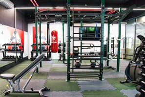 A gym with various exercise equipment, including a squat rack, dumbbells, and a punching bag. - Park Alley Apartments with Private Parking (Riga)