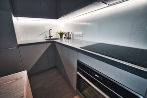 A modern kitchen with a built-in oven, dishwasher, and a black countertop. - Park Alley Apartments with Private Parking (Riga)