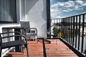 A balcony with a wooden floor, two wicker chairs, a table, and a Hisense inverter expert device.