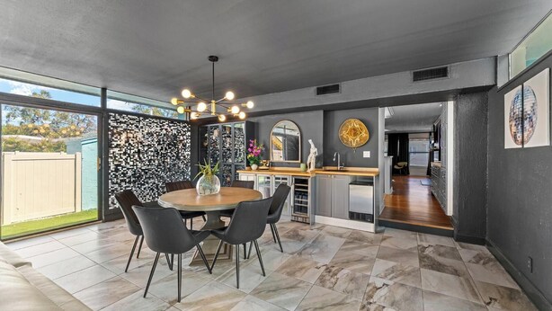 Uma cozinha moderna com área de jantar, grandes janelas e um detalhe decorativo na parede.