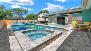 Piscina com hidromassagem, cercada por um espaço de área externa com mobiliário de jardim.