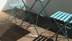 Terraço no telhado com mesa e cadeiras de metal azuis.