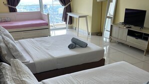 Ein Hotelzimmer mit zwei Betten, einem Schreibtisch, einem Stuhl, einem Fernseher und einem Fenster mit Vorhängen.