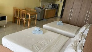 Ein Hotelzimmer mit zwei Betten, einer Küchenzeile, einer Essecke und einem Kleiderschrank.
