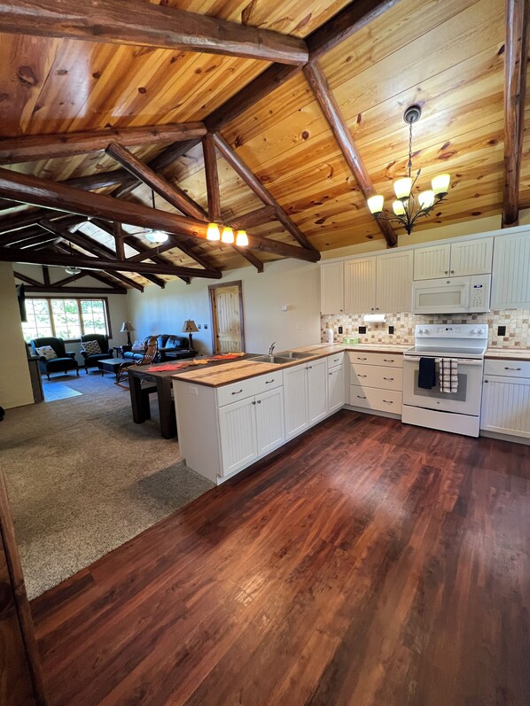 Una cocina amplia con vigas de madera, armarios blancos y una isla grande.