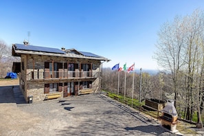 Ein Gebäude aus Stein mit Balkon, Solaranlage und Flaggen.