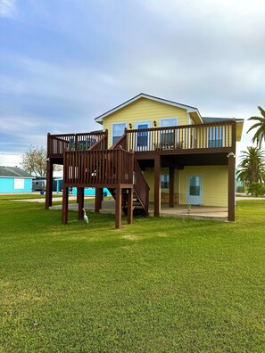 A two-story house with a wooden deck and a covered patio area.