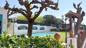 En swimmingpool, en pergola och en byggnad med en fasad beklädd med kakel.
