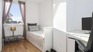 A small, tidy room with a bed, a desk, a chair, a lamp, and a window with curtains. - Room-spacious 3BR Home Peaceful Neighb (Lier)