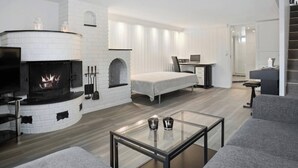 A modern living room with a fireplace, a sofa, a glass coffee table, and a desk with a computer. - Room-spacious 3BR Home Peaceful Neighb (Lier)