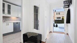 A modern kitchen with white cabinets and a black bench in a hallway with a view of a snowy landscape. - Room-spacious 3BR Home Peaceful Neighb (Lier)