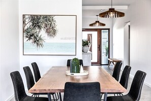 Een eetgedeelte met een houten tafel, zwarte stoelen, een ingelijste foto en een hanglamp.