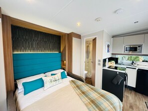 A bedroom with a bed, a bathroom, and a kitchenette. - Ravenswood Pod near Fort William (Fort William)