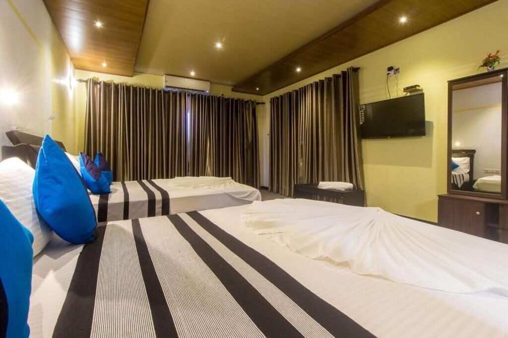 A hotel room with two beds, a flat-screen TV, a mirror, and a wooden ceiling.