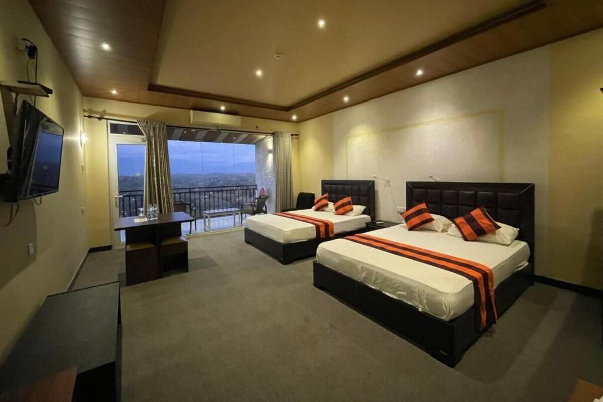 Ein Hotelzimmer mit zwei Betten, einem Fernseher, einem Balkon mit Blick und einem Schreibtisch.
