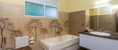 A bathroom with a bathtub, toilet, and sink, with a window above the toilet and a mirror above the sink.