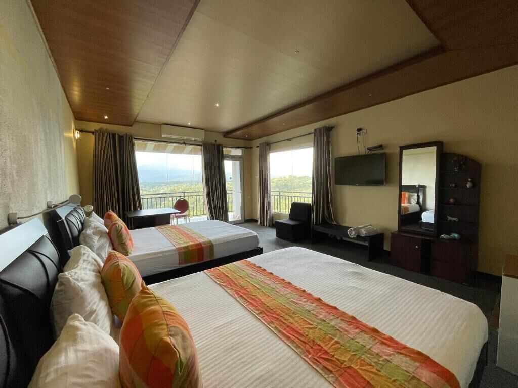 Habitación de hotel con dos camas, un escritorio, un televisor y un balcón con vistas.