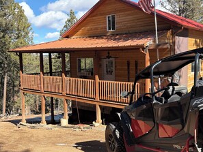 A wooden cabin with a porch, a covered deck, and a vehicle parked in front. - Terrific 2-bedroom country house in charming Woodland Park (Woodland Park)