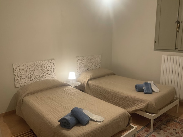 A room with two beds, a nightstand with a lamp, and a radiator. - Oasi del Silenzio Apartment in Relais with panoramic SPA (Piea)
