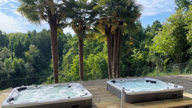 Two hot tubs on a wooden deck with a forest backdrop. - Oasi del Silenzio Apartment in Relais with panoramic SPA (Piea)