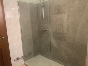 Une cabine de douche fermée par des parois en verre, dotée d’un pommeau de douche à main, d’un robinet mural et d’une porte à clé.