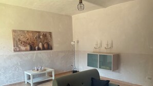 A living room with a sofa, a painting, a floor lamp, and a cabinet. - Oasi del Silenzio Apartment in Relais with panoramic SPA (Piea)