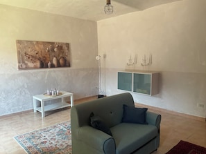 Un salon avec un canapé, un tableau, une lampe sur pied et un meuble.
