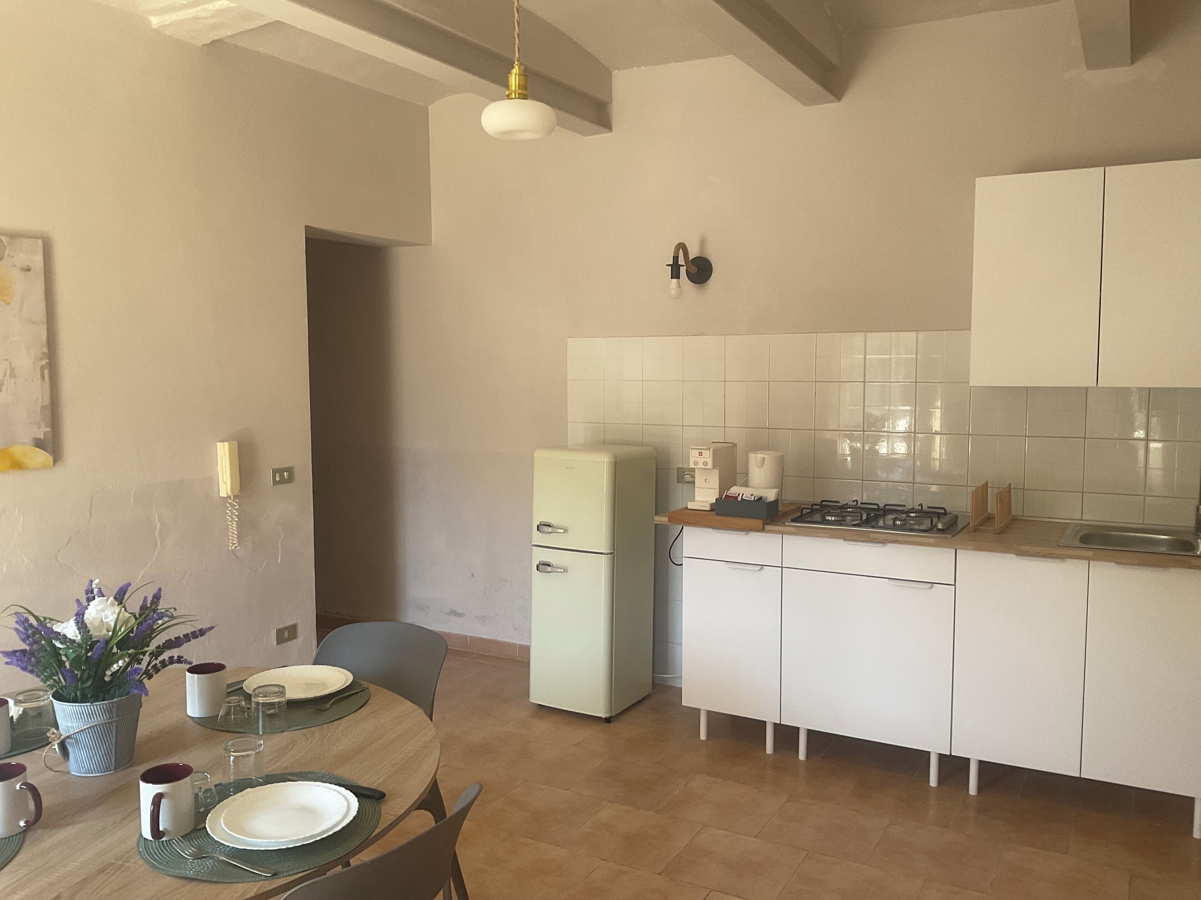 Une cuisine avec des meubles blancs, une cuisinière à gaz et un réfrigérateur.