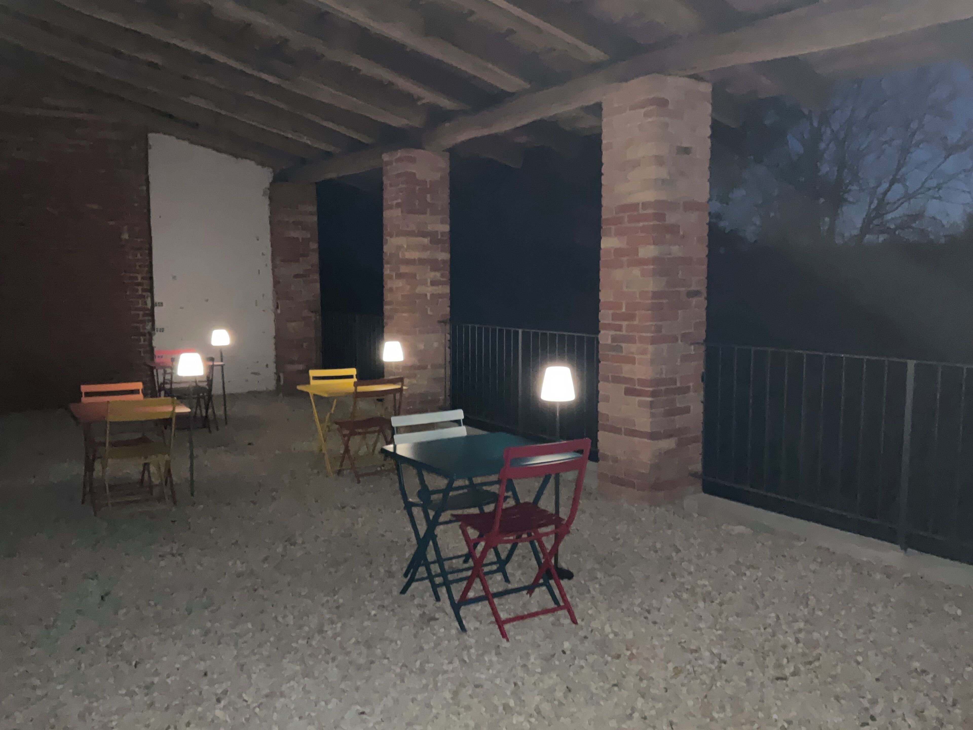 An outdoor patio area with brick pillars, a table, and chairs.