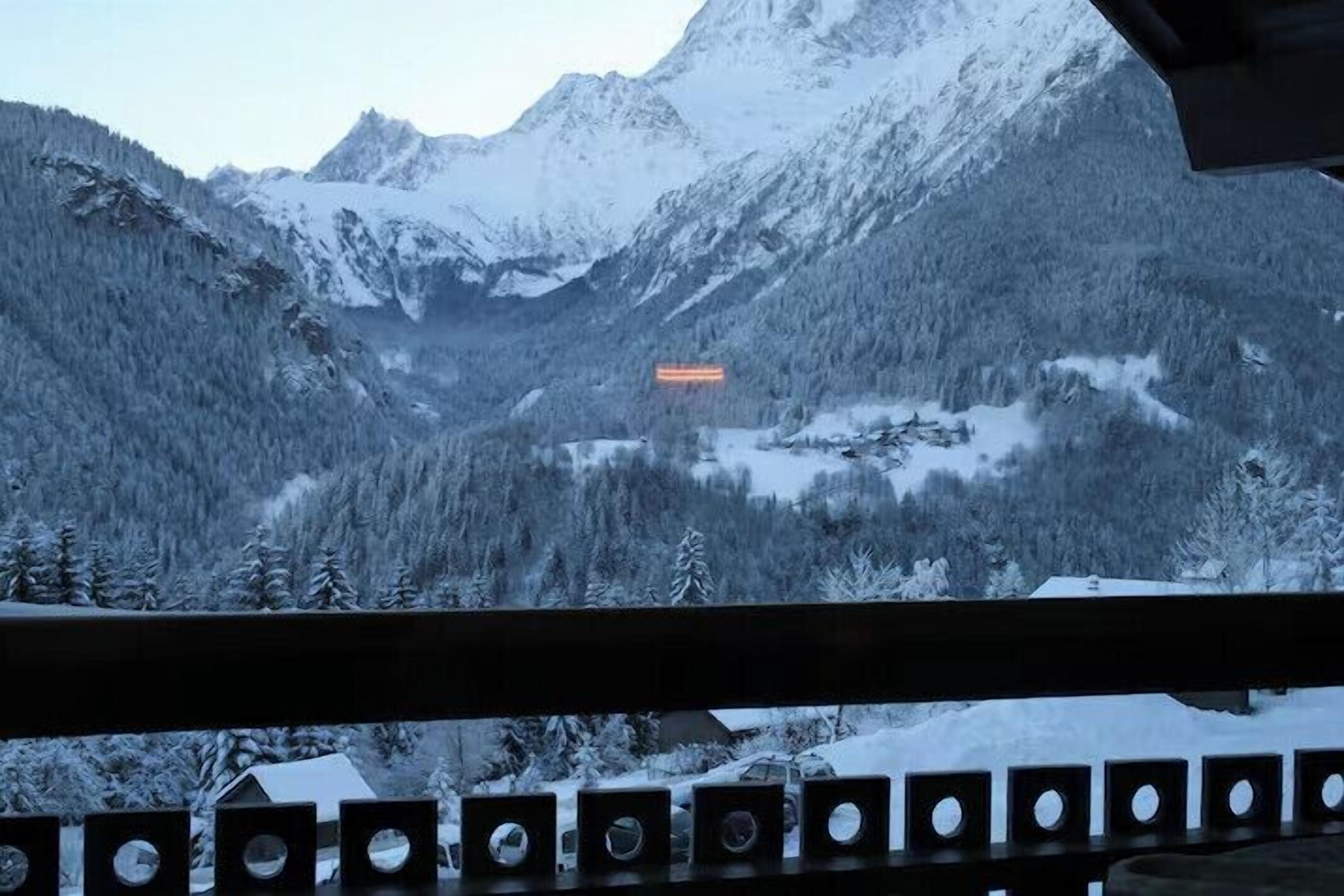 Eine Berglandschaft mit schneebedeckten Bäumen und einer Holzhütte.