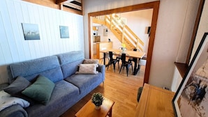 Ein gemütliches Wohnzimmer mit einer Couch, einem Holztisch und einer Treppe, die zur Küche führt.