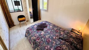 A bedroom with a bed, a chair, a wardrobe, a mirror, and a window. - Beautiful 54 m² apartment with parking in Nantes (Nantes)