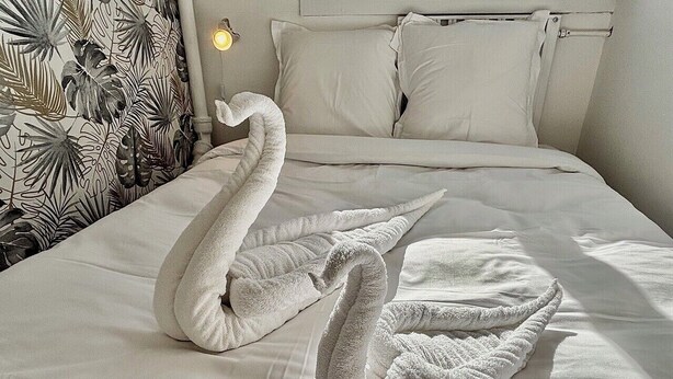 Una cama con toallas con forma de cisne y una pared con estampado floral.