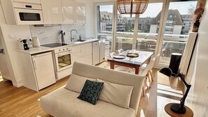 Una cocina moderna con armarios blancos, horno empotrado y un comedor con mesa y sillas.